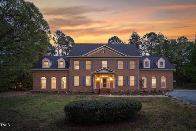 colonial inspired home with a front lawn and brick siding