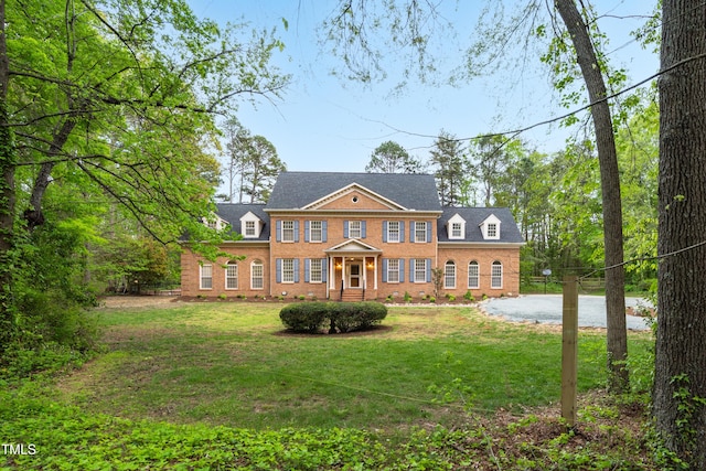 colonial inspired home with brick siding and a front yard