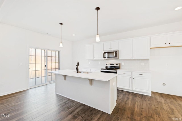 kitchen with dark wood finished floors, white cabinets, a sink, stainless steel appliances, and decorative backsplash