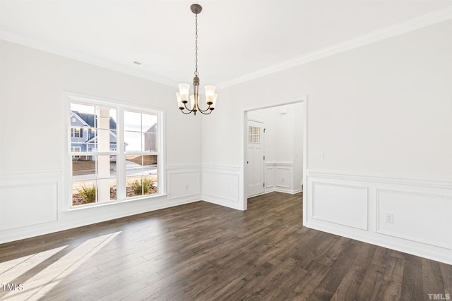 unfurnished dining area featuring a chandelier, dark wood-style flooring, crown molding, and a wainscoted wall