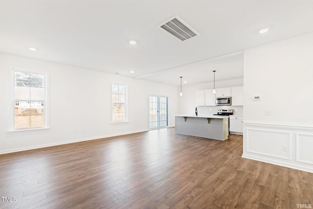 unfurnished living room featuring visible vents, baseboards, recessed lighting, and wood finished floors