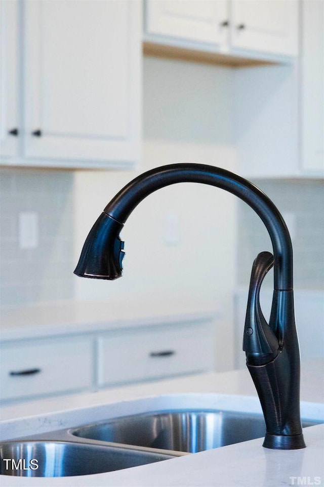 interior details with light countertops, a sink, and white cabinetry
