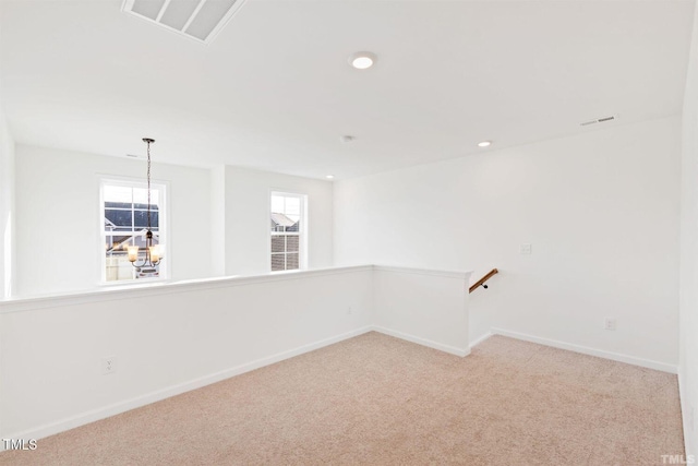 spare room featuring a chandelier, visible vents, baseboards, and carpet floors