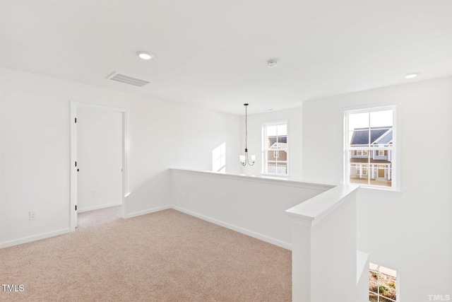 empty room featuring an inviting chandelier, visible vents, recessed lighting, carpet flooring, and baseboards