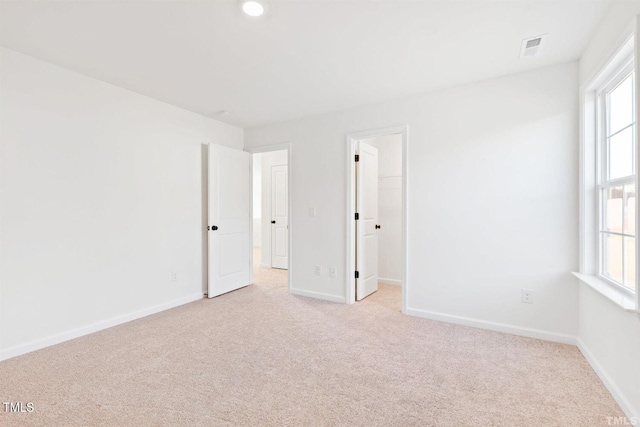 unfurnished room featuring visible vents, light colored carpet, and baseboards