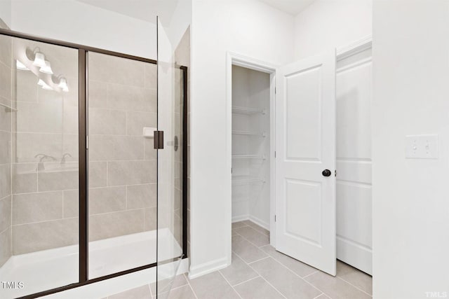 full bath with a walk in closet, a shower stall, and tile patterned flooring