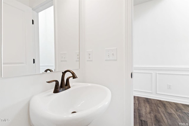 bathroom with a decorative wall, a sink, and a wainscoted wall
