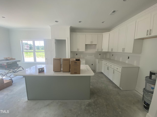 102 Rae Dr, Pikeville, NC 27863 - kitchen with unfinished concrete flooring, a center island, white cabinetry, and crown molding