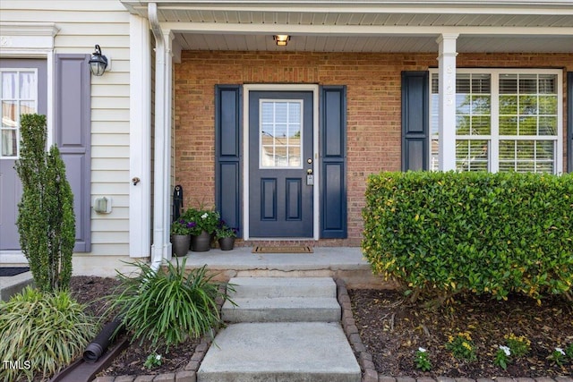 entrance to property with a porch and brick siding