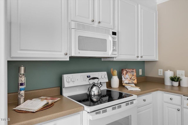 kitchen featuring white cabinets and white appliances