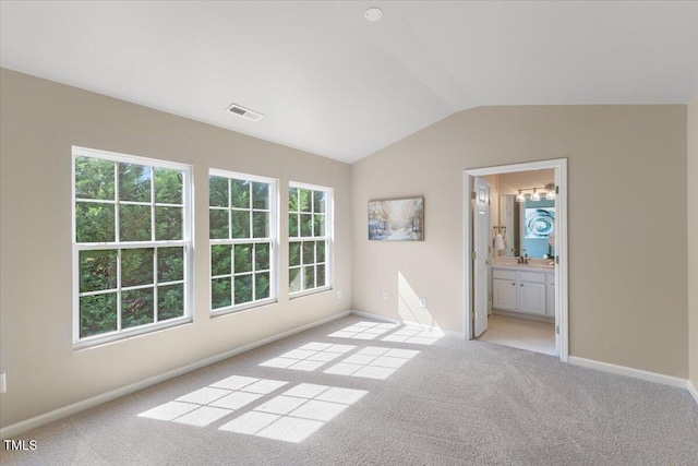 unfurnished bedroom with multiple windows, light colored carpet, visible vents, baseboards, and lofted ceiling