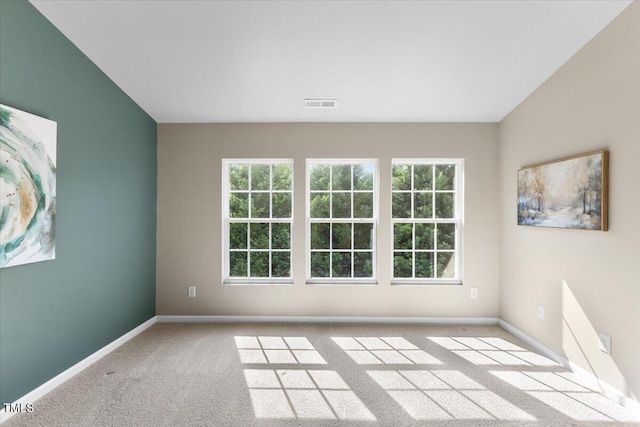 carpeted empty room featuring baseboards, a healthy amount of sunlight, and visible vents