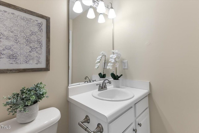 half bathroom featuring vanity, toilet, and a notable chandelier