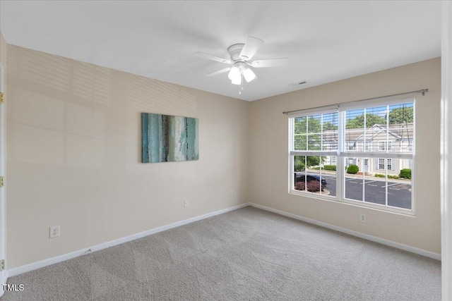 carpeted spare room with a ceiling fan, baseboards, and visible vents