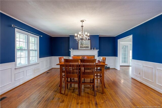 211 Edgewood Ave, Clinton, NC 28328 - dining area with a chandelier, hardwood / wood-style flooring, a textured ceiling, and crown molding
