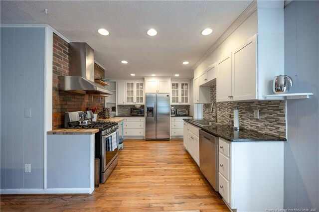 211 Edgewood Ave, Clinton, NC 28328 - kitchen with light wood-type flooring, wall chimney range hood, white cabinets, a sink, and stainless steel appliances