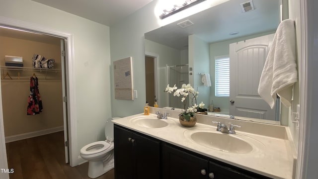 126 Willow Weald Ct, Fuquay Varina, NC 27526 - bathroom with double vanity, a walk in closet, toilet, wood finished floors, and a shower with door