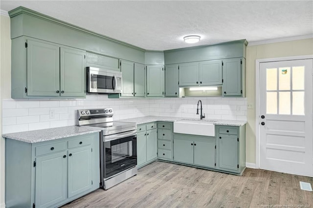 3014 Akron Dr, Hope Mills, NC 28348 - kitchen with a sink, light wood-type flooring, a textured ceiling, stainless steel appliances, and decorative backsplash