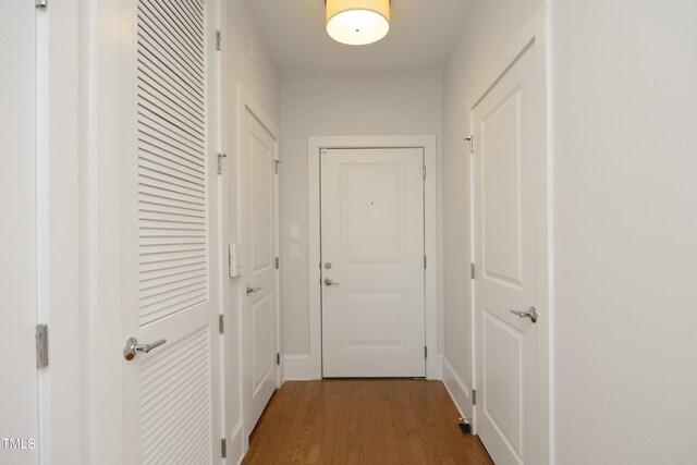 hall with baseboards and wood finished floors