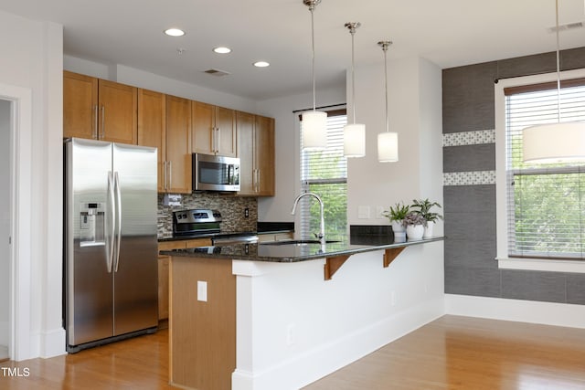 kitchen featuring a peninsula, visible vents, appliances with stainless steel finishes, a sink, and light wood finished floors