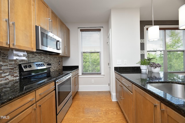 kitchen with decorative backsplash, plenty of natural light, baseboards, and stainless steel appliances