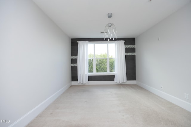 spare room featuring light colored carpet, visible vents, baseboards, and a notable chandelier