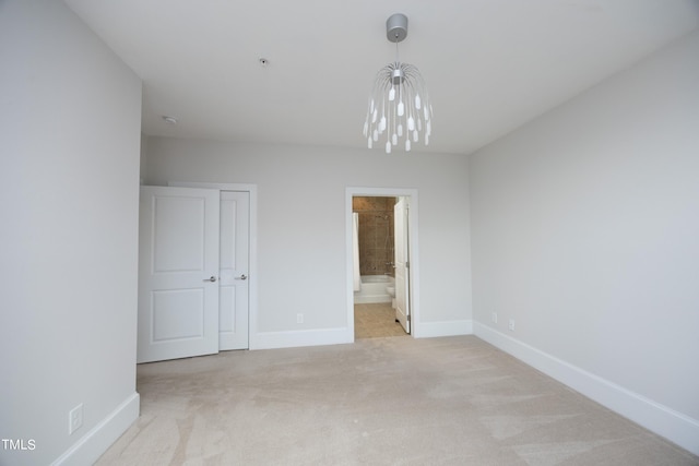 unfurnished bedroom featuring ensuite bath, light colored carpet, and baseboards