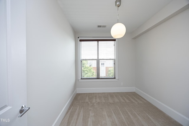 empty room featuring visible vents, baseboards, and light carpet