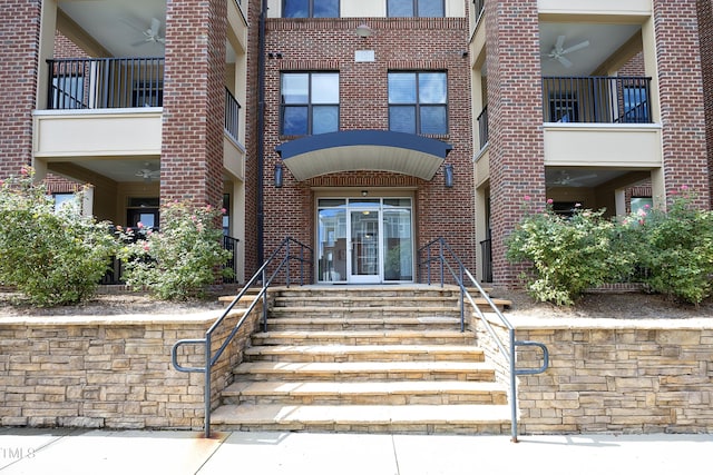 view of exterior entry featuring a ceiling fan and brick siding