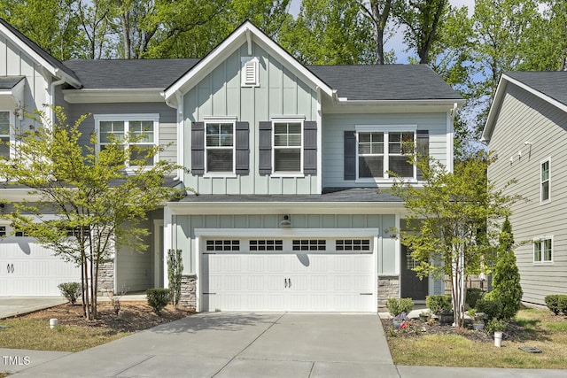 view of front facade with board and batten siding, stone siding, a garage, and driveway
