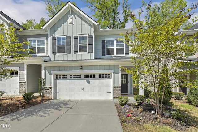 view of front of house with board and batten siding, stone siding, a garage, and concrete driveway