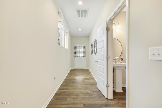 corridor featuring visible vents, baseboards, and dark wood-style floors