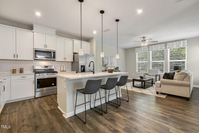 kitchen featuring light countertops, a sink, stainless steel appliances, decorative backsplash, and a breakfast bar area