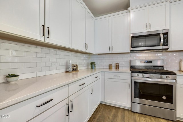 kitchen with stainless steel appliances, white cabinets, backsplash, and dark wood-style floors
