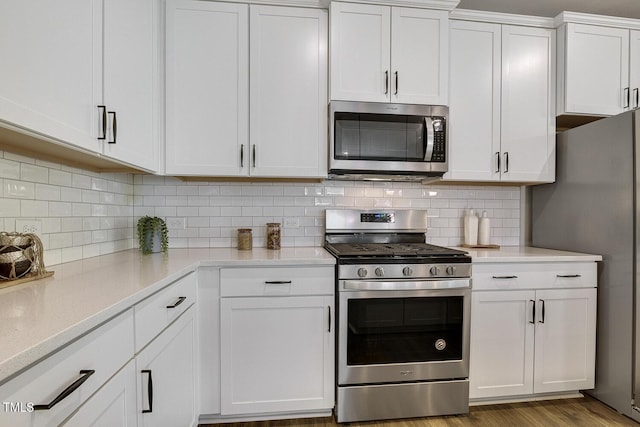 kitchen with decorative backsplash, white cabinets, and stainless steel appliances