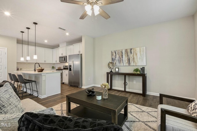living room featuring a ceiling fan, visible vents, recessed lighting, dark wood-style flooring, and baseboards