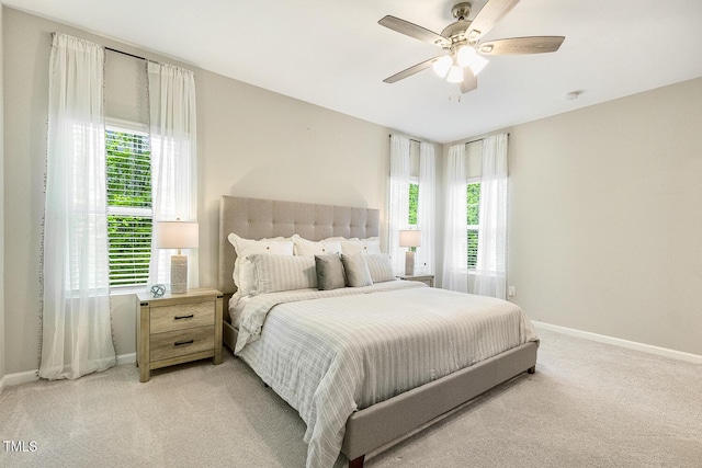 bedroom with light carpet, multiple windows, and baseboards
