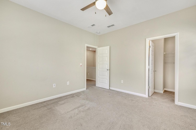 unfurnished bedroom featuring a walk in closet, visible vents, and carpet floors