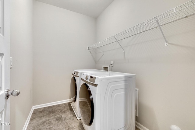clothes washing area with baseboards, washing machine and dryer, and laundry area
