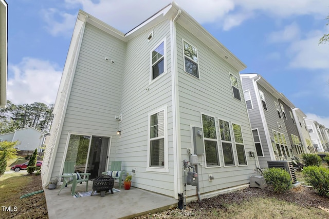 rear view of house with a fire pit and a patio