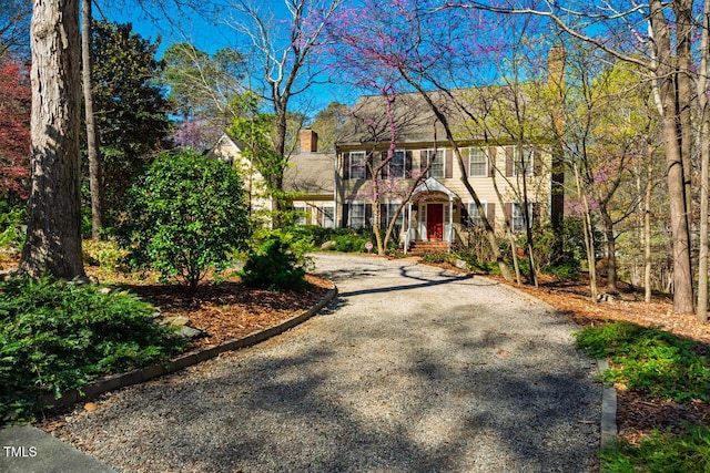 colonial home featuring aphalt driveway and a chimney