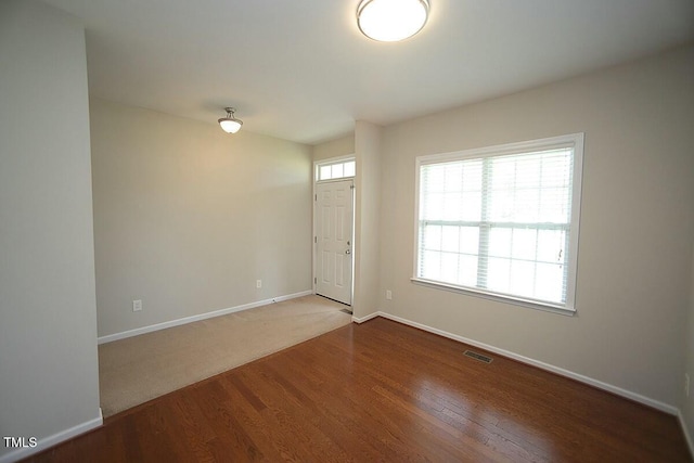 entryway with wood finished floors, baseboards, and visible vents