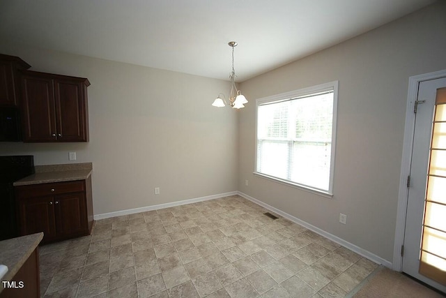 unfurnished dining area with stone finish floor, visible vents, baseboards, and an inviting chandelier
