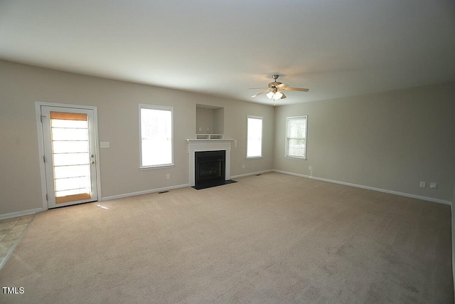 unfurnished living room featuring a fireplace with flush hearth, light carpet, ceiling fan, and baseboards