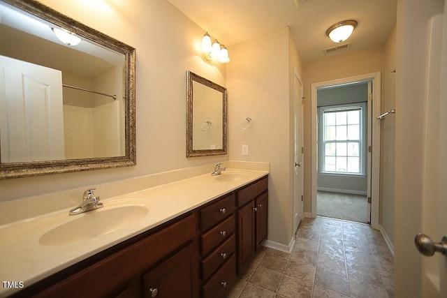 full bath with baseboards, double vanity, a sink, and visible vents