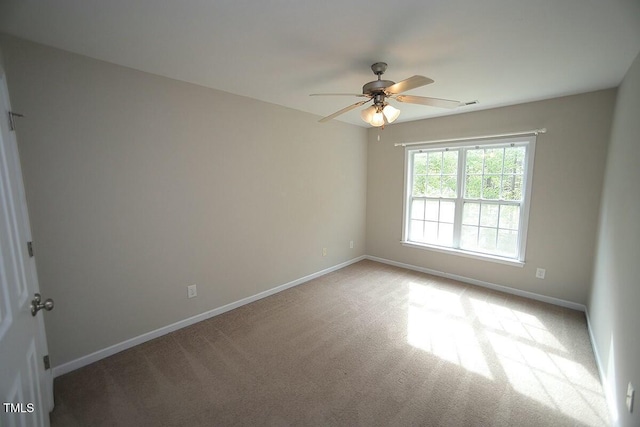 spare room featuring light colored carpet, ceiling fan, and baseboards