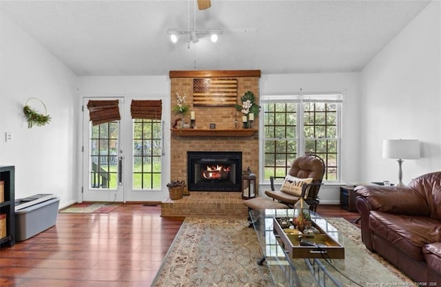 living area featuring a fireplace, ceiling fan, and wood finished floors