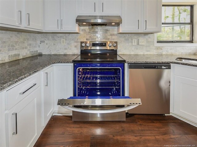494 Wilder Dr, Fayetteville, NC 28314 - kitchen with appliances with stainless steel finishes, dark wood-style floors, white cabinetry, dark stone counters, and extractor fan