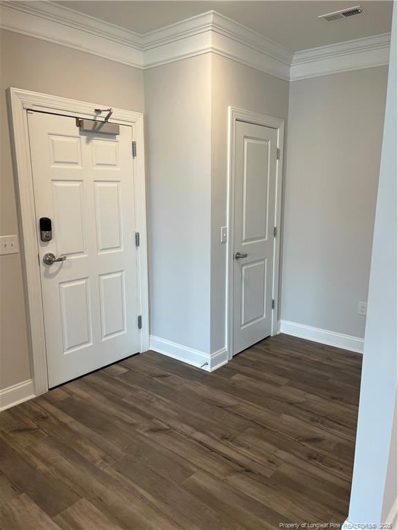 foyer featuring crown molding, baseboards, dark wood finished floors, and visible vents