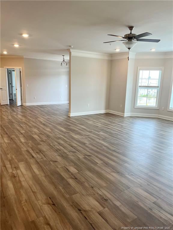 unfurnished room featuring crown molding, baseboards, dark wood-style flooring, and ceiling fan with notable chandelier